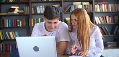students researching in a library using laptop